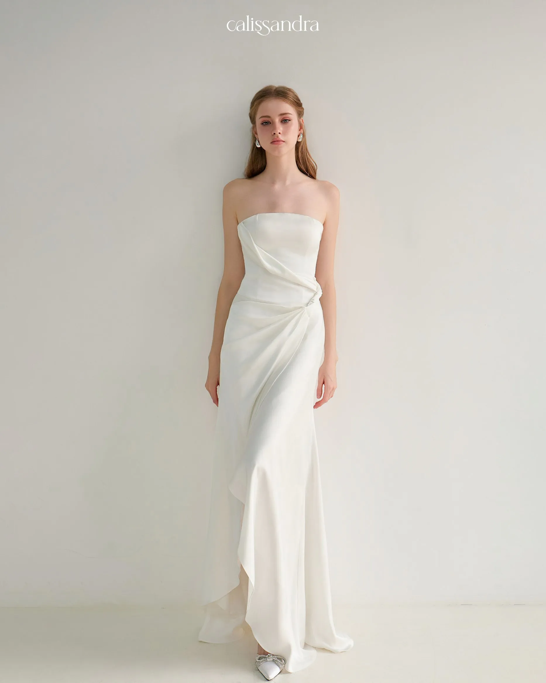 Close-up front view of Angeletta white strapless maxi dress highlighting its elegant cuffed strapless bodice and asymmetrical waist draping by Calissandra
