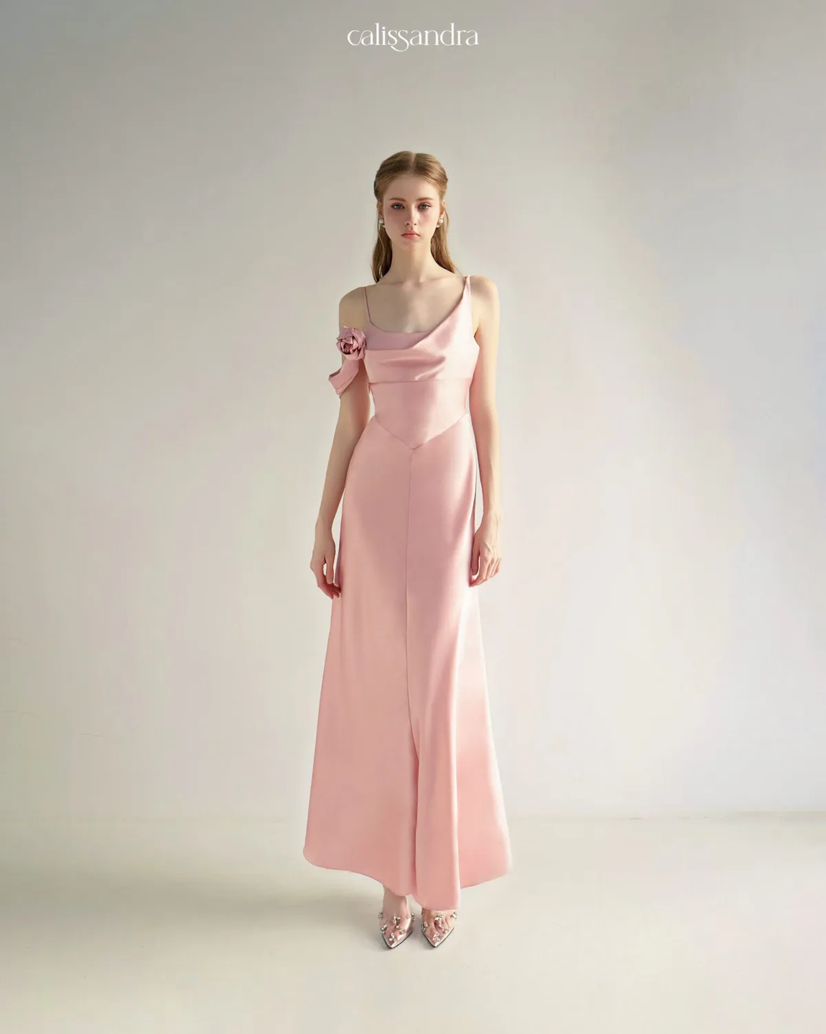 Three-quarter lifestyle view of Sanee white satin evening gown with black lace halter neck trim showcasing its long, flowing skirt next to a minimalist ceramic vase by Calissandra
