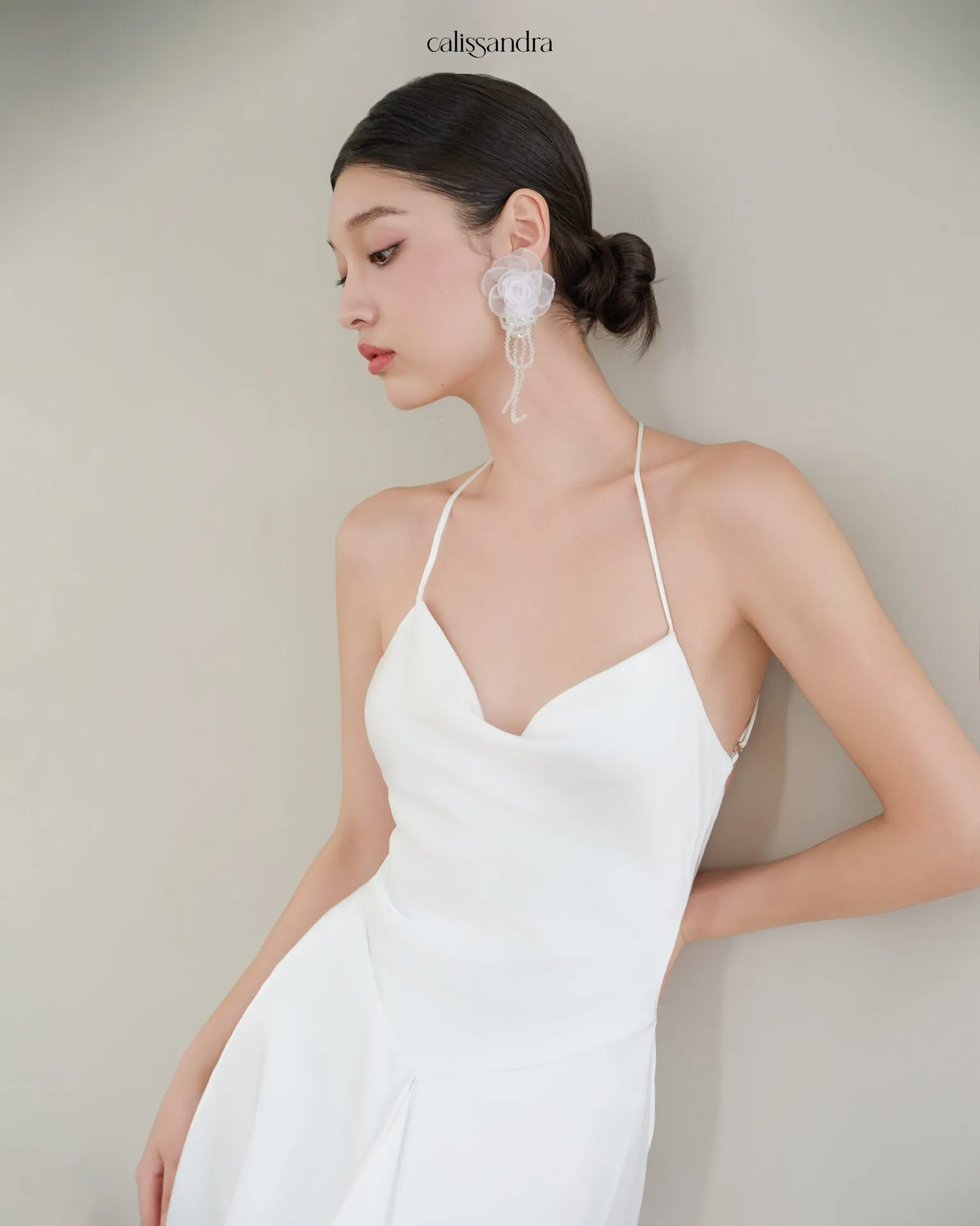 Full-length view of Opaline luxury ivory white silk satin formal evening gown, featuring a cowl halter neckline and an asymmetrical ruffled hem over delicate lace lining by Calissandra