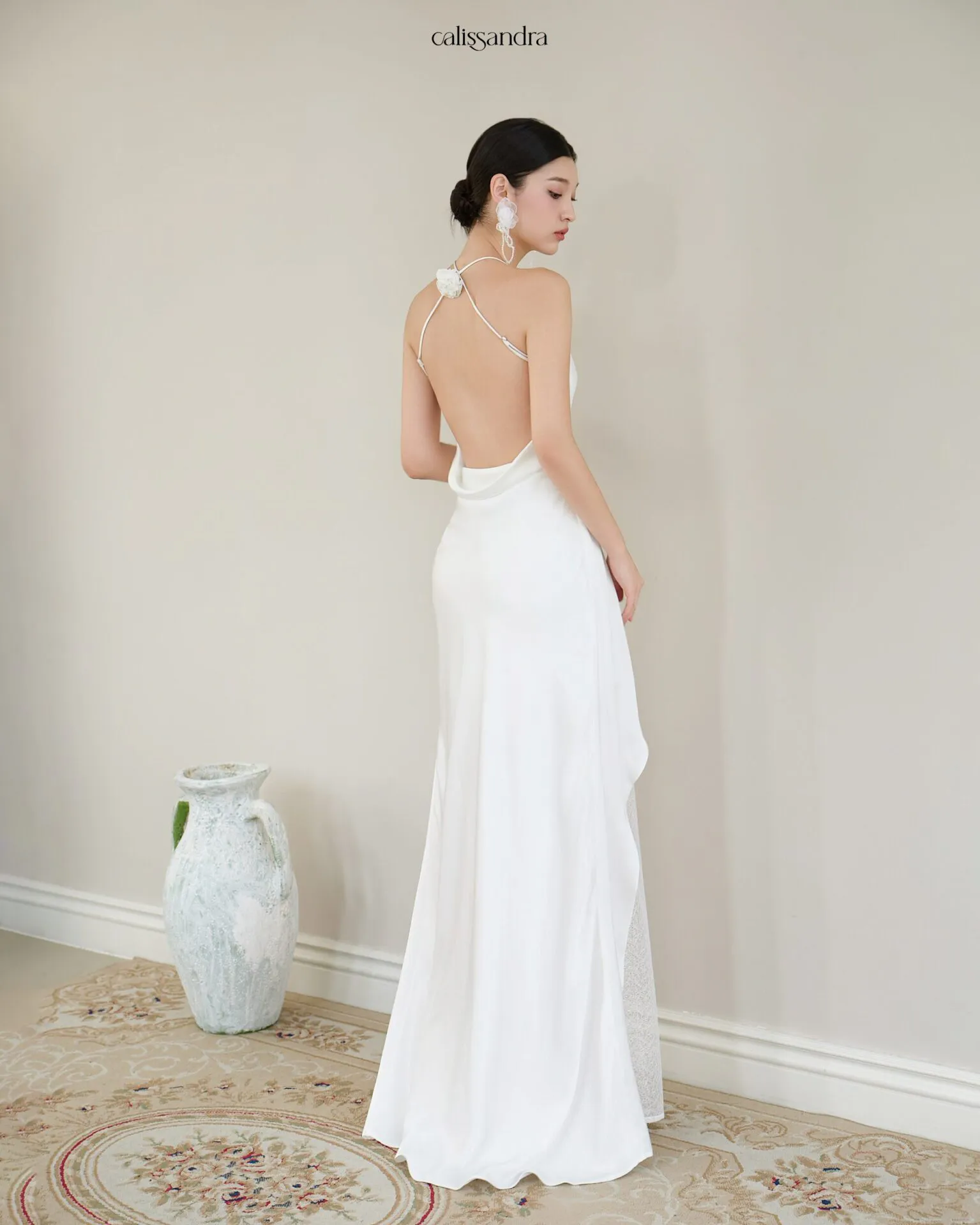 Full-length view of Opaline luxury ivory white silk satin formal evening gown, featuring a cowl halter neckline and an asymmetrical ruffled hem over delicate lace lining by Calissandra
