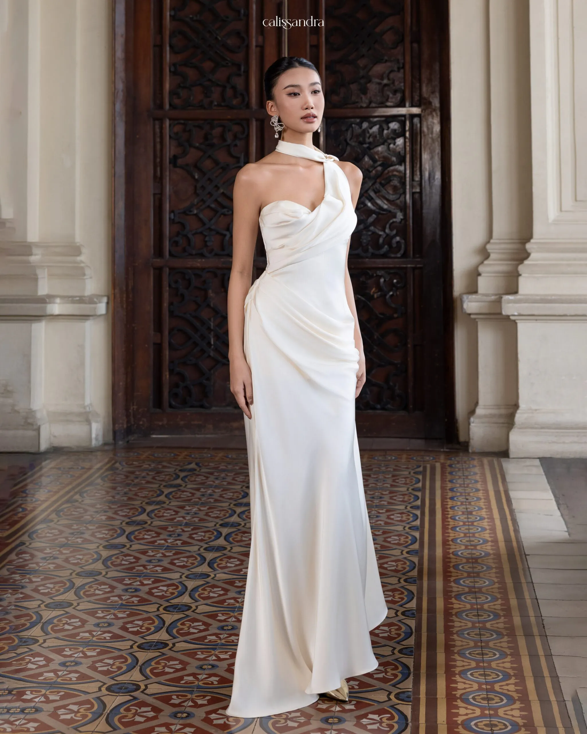 Full-length view of Adalicia luxury ivory white silk satin bridal gown, featuring an asymmetrical one-shoulder design with an integrated choker halter neck and elegant draped bodice by Calissandra