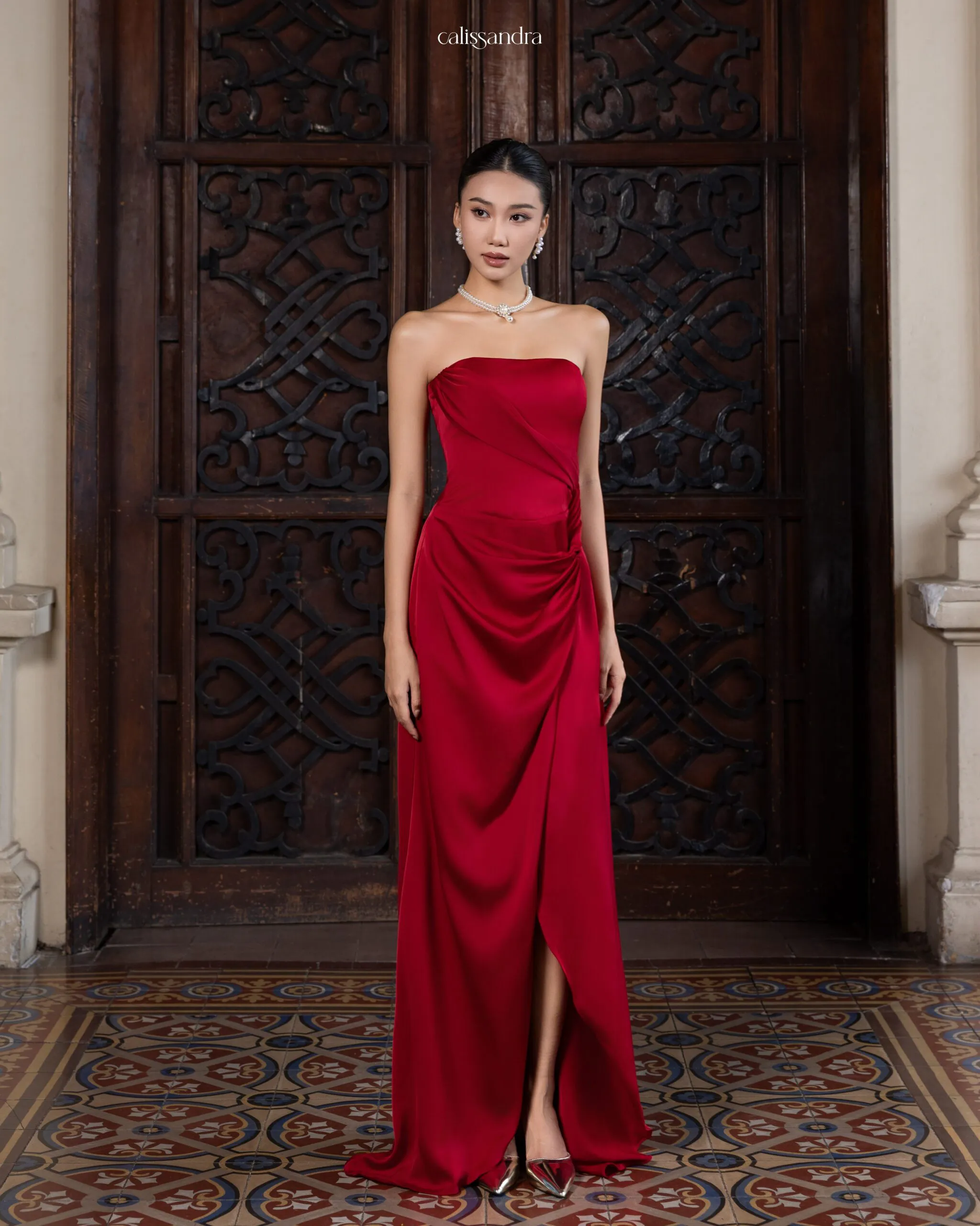 Full-length view of Angeletta luxury burgundy red silk satin strapless evening gown, featuring an elegant side gathered draping and a sophisticated front slit by Calissandra