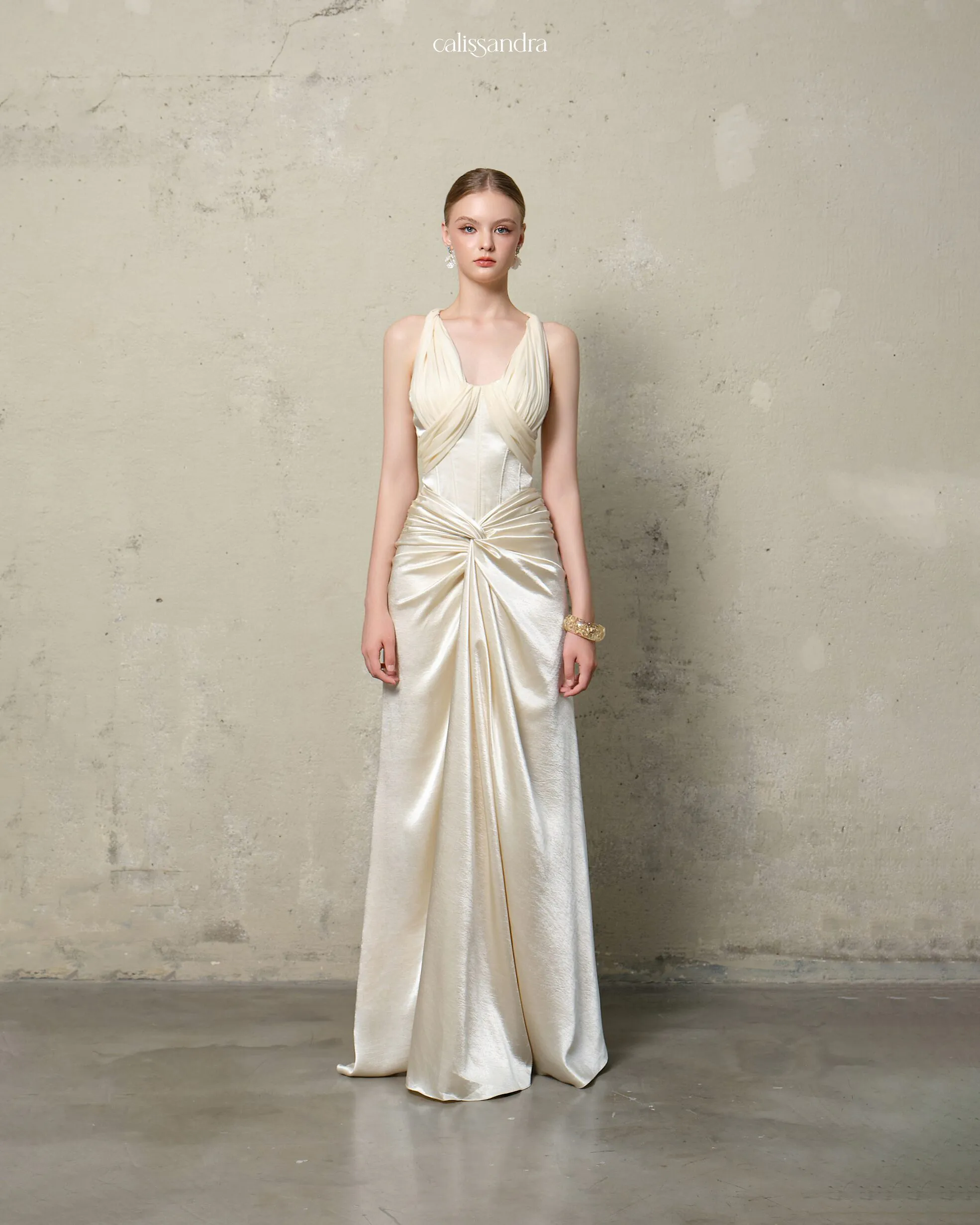 Full-length view of Delarine luxury pearl ivory silk satin formal bridal gown, featuring a pleated chiffon plunging V-neckline and a dramatic central knot draping by Calissandra