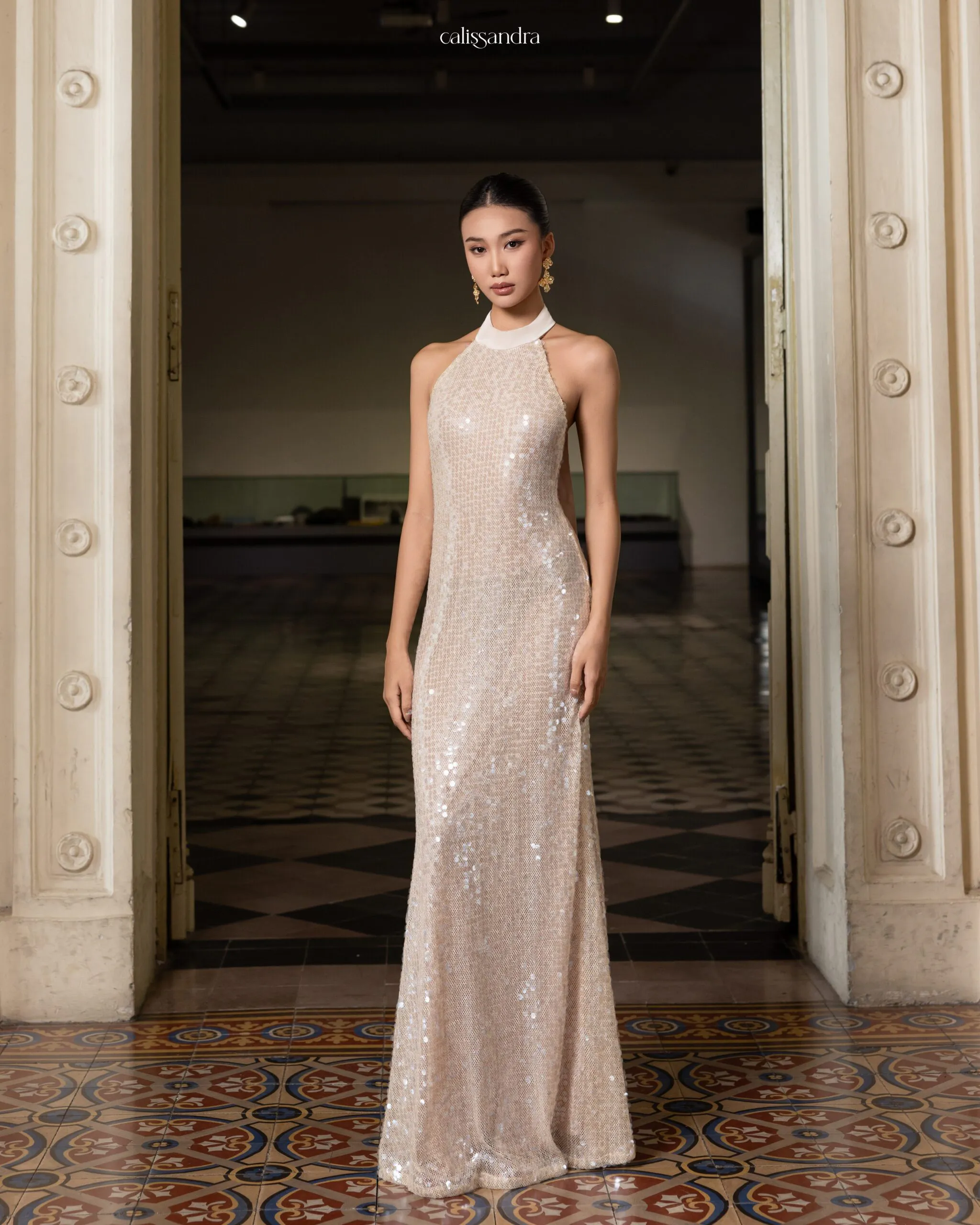 Full-length view of Elissara luxury shimmering champagne beige sequin formal evening gown, featuring a sophisticated high halter neckline by Calissandra