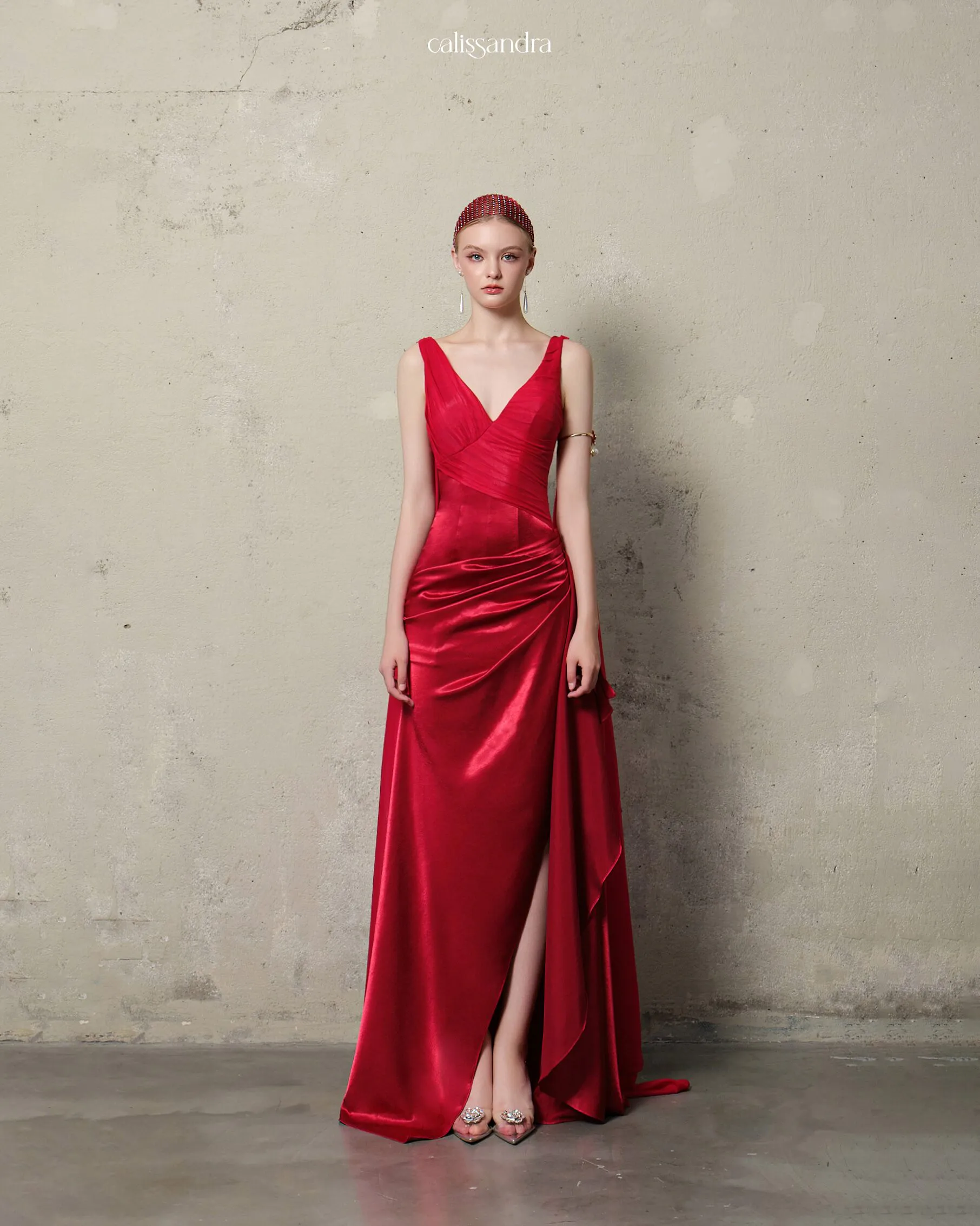 Full-length view of Velorine luxury ruby red silk satin evening gown, featuring a plunging V-neckline, a high side slit, and an elegant flowing shoulder cape by Calissandra